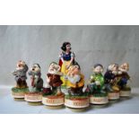 A set of glazed ceramic figures of Snow White and the Seven Dwarves by Schmid, each figure rotates
