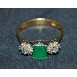 Emerald colour and diamond 18ct three-stone ring, the central stone flanked by daisy diamond