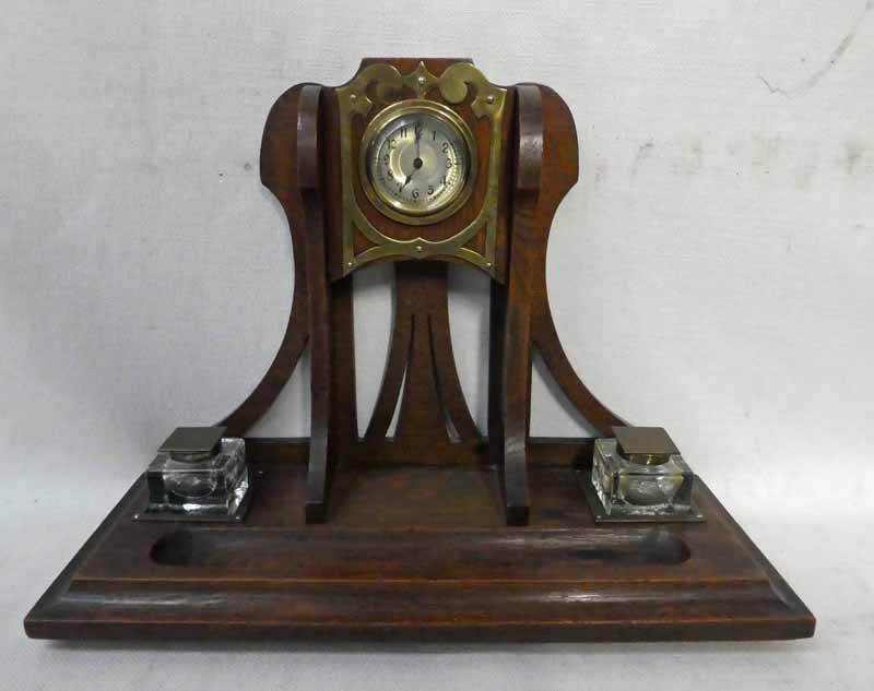 An Arts and Crafts oak Desk Stand, vertical bracket, pierced and set centrally with a clock, moulded