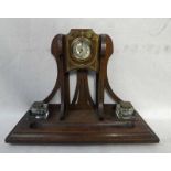 An Arts and Crafts oak Desk Stand, vertical bracket, pierced and set centrally with a clock, moulded
