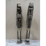 A pair of tall carved tribal figures formed as women with elongated arms and kerfs to depict ribs on