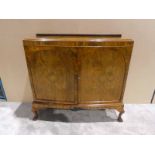 A mid 20th century walnut two-door Cabinet, slightly bowed, the hinged doors enclosing shelves,