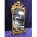A Rococo style gilt frame Mirror with shell and scroll carved top and bottom, 102cm by 47cm