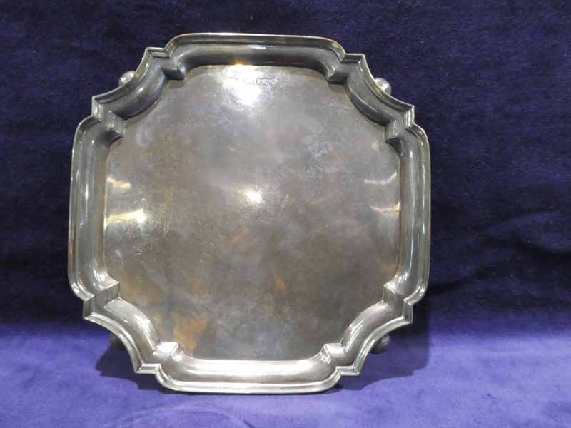 A mid 20th century silver four footed Salver, square with canted corners, raised rim on shallow ball