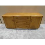 A mid/late 1970's Ercol light ash sideboard, rectangular top over three central drawers, the top