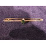A 9ct gold Bar Brooch set with a single oval emerald colour stone, 2.8g gross, 6cm long
