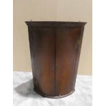 A Georgian mahogany two-door bow fronted wall hanging Corner, shelved interior, 102cm high by 70cm