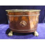 An early 20th century planished copper Coal Bin, oval form with brass lip, embossed rose to opposing