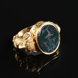 AN 18K YELLOW GOLD AND BLOODSTONE MEN'S SIGNET RING, the oval cut stone engraved with a crest of