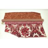 A roll of red and cream cut floral fabric, and a roll of coral cotton velvet