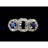 An 18 cart gold ring set three sapphires with diamond surround - size J 1/2