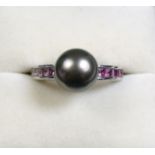 An 18 carat gold ring set grey pearl flanked by pink sapphires, size J 1/2