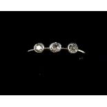 An Edwardian collett set 18 carat gold and platinum three stone diamond ring
