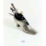 A pewter pin cushion in the form of a ladies shoe - with various hat pins