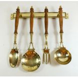 A set of four French brass and turned wood kitchen serving implements on hanging rack