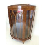 A 1930's walnut demi-lune display cabinet on squat supports