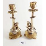 A pair of French brass candlesticks decorated with putti to stems holding dragon flies 19.5cm