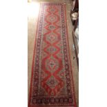 A red ground Turkoman style runner with geometric motifs 245 x 66cm