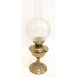 A brass oil lamp with etched glass globe shade
