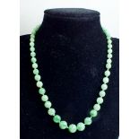 A string of jade beads with 18 carat white gold diamond set clasp 42cm