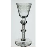 An 18th century wine glass with scrollwork and floral engraved decoration raised on double knopped