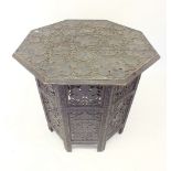 A Moroccan octagonal carved wood occasional table carved vines, on folding base