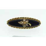 A Victorian black stone and gold oval mourning brooch with seed pearl set leaf motif and hair locket