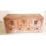 A late 19th century Chinese pine side cabinet with three cupboards and four drawers to base, brass
