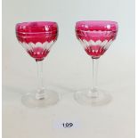 A pair of early 20th century cranberry glasses with overlaid and cut decoration, 13cm tall