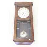 A 1930's oak wall clock with glazed door