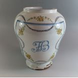 A 19th century Delft drug jar painted initials within floral swag surround, 24cm tall, a/f