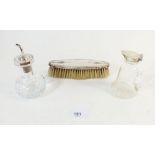 A cut glass silver topped cruet bottle, a cut glass and silver oil jug and a sliver brush, worn