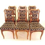 A set of six French Art Nouveau carved light wood dining chairs with sinuous supports to backs and
