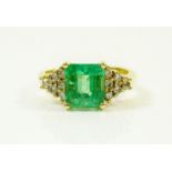 An 18 carat yellow gold emerald and diamond ring, the two carat emerald flanked by twelve brilliant