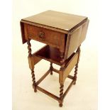 An oak 1920's occasional table with drop flaps over book trough