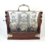 A mahogany tantalus with three cut glass decanters and silver plated mounts plus three decanter