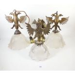 A pair of double headed eagle form brass light fittings with clear glass frilled shades and one