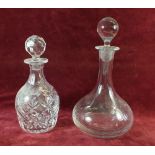 A cut glass decanter and a clear glass decanter