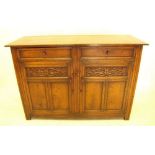 An oak sideboard with two drawers over carved and panelled cupboard doors 137cm wide