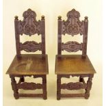 A pair of 20th century Jacobean style oak hall chairs with carved arch top panel backs