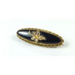 A Victorian black stone and gold oval mourning brooch with seed pearl set leaf motif and hair locket