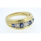 An 18 ct gold ring set three diamonds and four sapphires 6.8g, size B