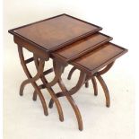 A Bevan & Funnell nest of three mahogany occasional tables on X frame supports