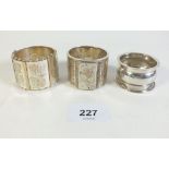 Three silver napkin rings, two inset and engraved with yellow metal floral decoration and one plain,