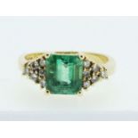 An 18 carat yellow gold emerald and diamond ring, the two carat emerald flanked by twelve