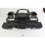 A Victorian black lacquer pen and ink stand with two glass inkwells and central dolphin support