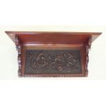 An Arts & Crafts mahogany wall shelf with floral carved decoration