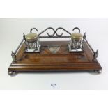 An Edwardian oak inkstand set on four silver plated bun feet with matching inkwells and central