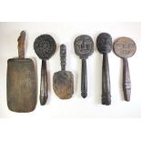 A group of carved wooden tribal items including three face form paddles or markers and one floral