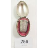 A silver thimble in gilt metal egg form holder